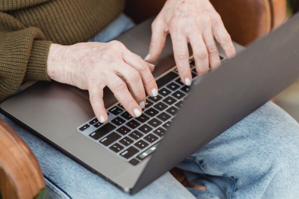 A closeup of a woman sitting on a chair and typing on her laptop