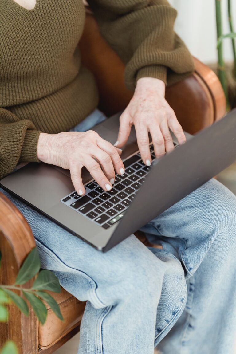 A closeup of a woman sitting on a chair and typing on her laptop